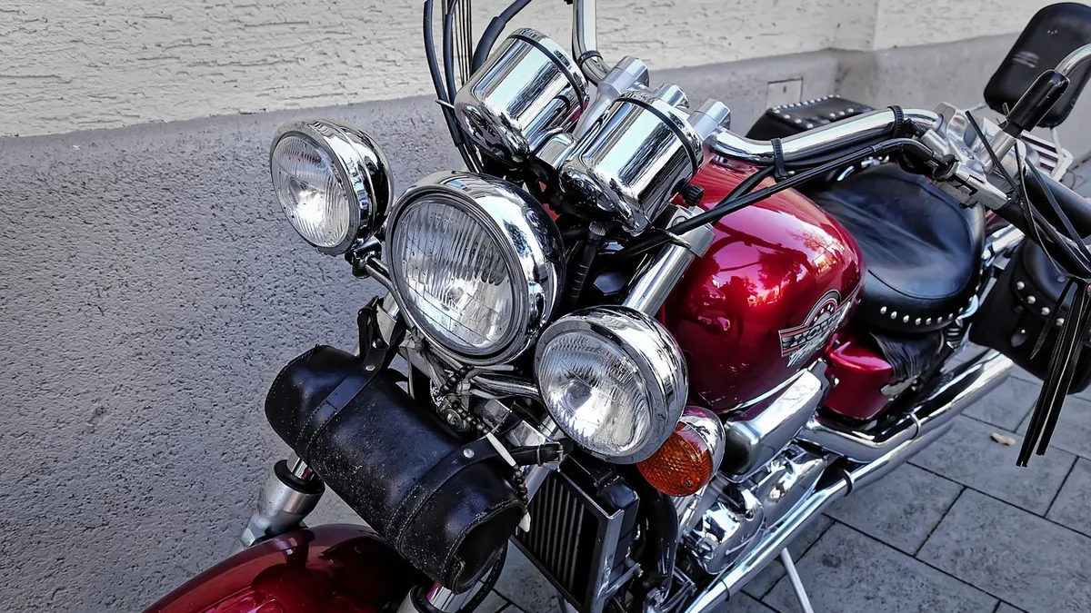 Moto vermelha com farol redondo estacionada na calçada